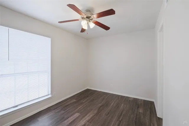 an empty room with wooden floor and ceiling fan