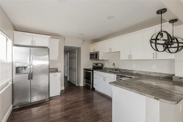 a kitchen with stainless steel appliances granite countertop a refrigerator a stove and a sink