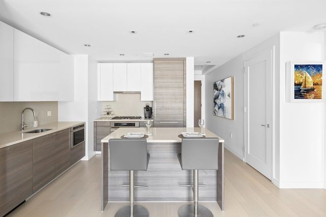 a kitchen with stainless steel appliances granite countertop a stove top oven a sink a dining table and chairs with white cabinets