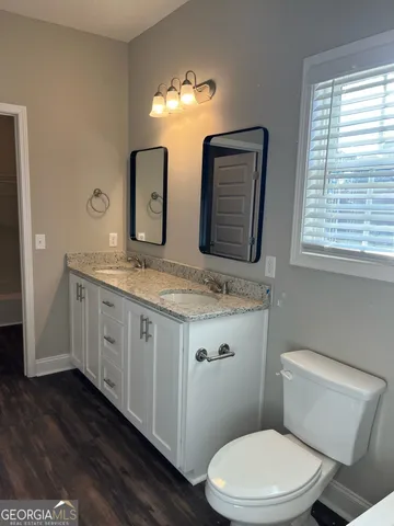 a bathroom with a granite countertop toilet sink and mirror
