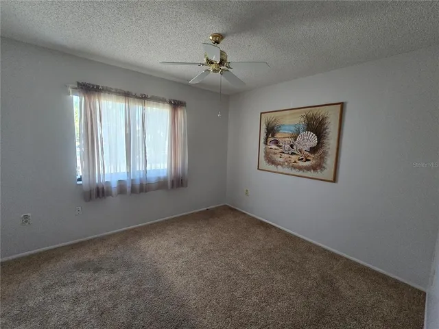 an empty room with windows and ceiling fan