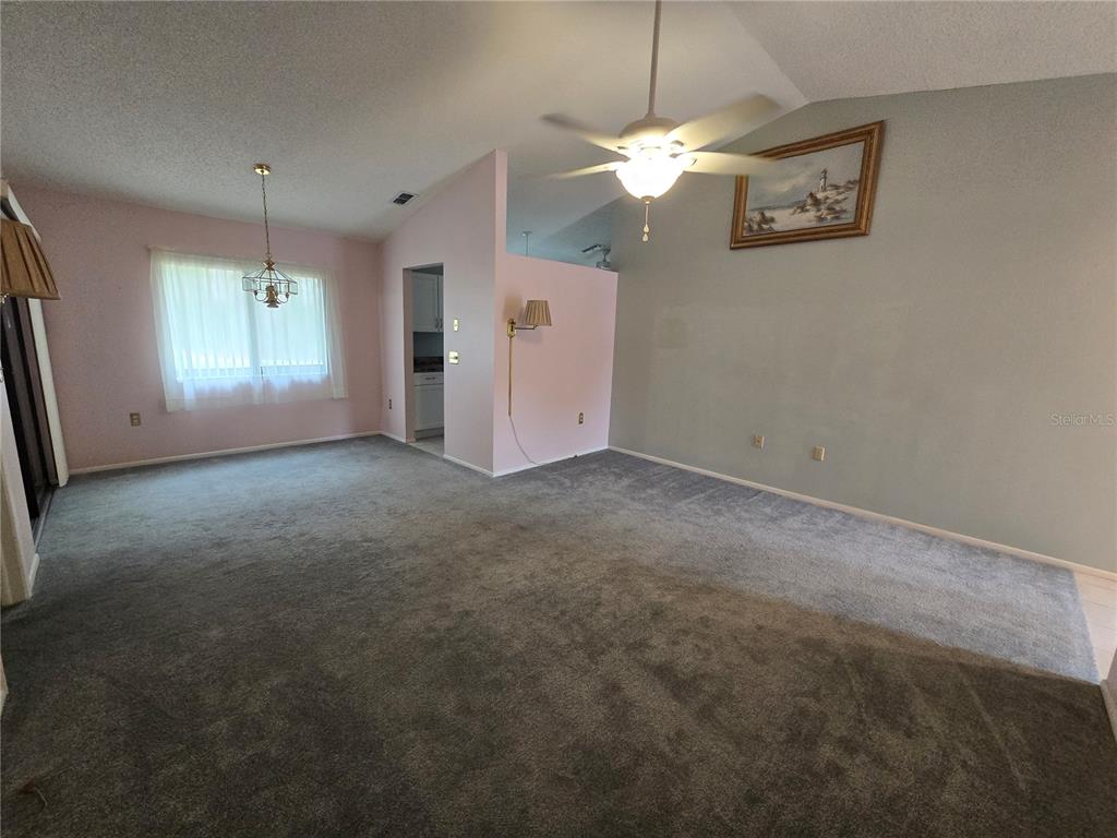 8055 Picketts Court, Unit 8055 Weeki Wachee, FL 34613 - Photo 4 of 22 an empty room with a chandelier fan and windows
