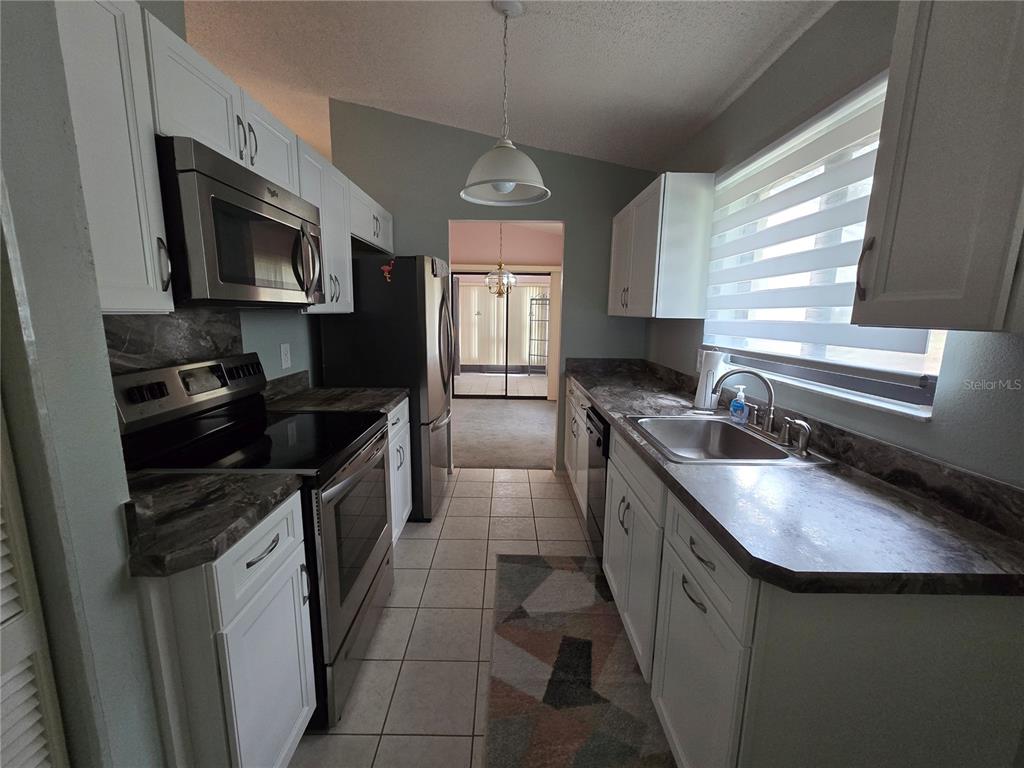 8055 Picketts Court, Unit 8055 Weeki Wachee, FL 34613 - Photo 9 of 22 a kitchen with granite countertop stainless steel appliances a sink stove top oven and cabinets
