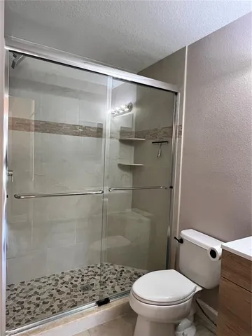 a view of a white house sitting in a big yard with large trees