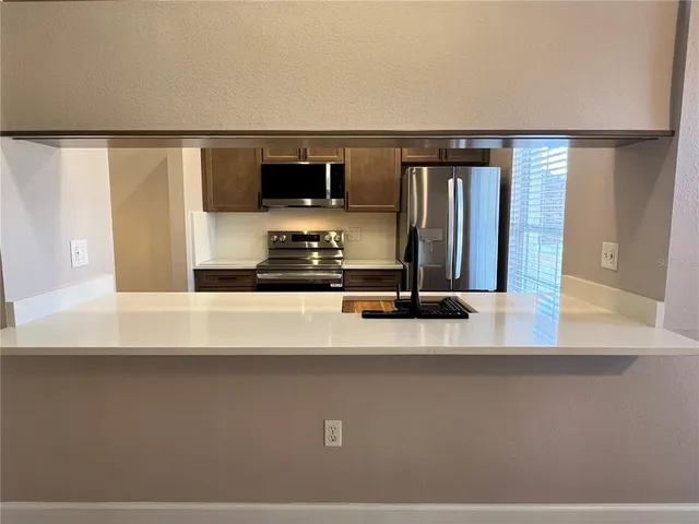 a kitchen with stainless steel appliances granite countertop a sink and wooden cabinets