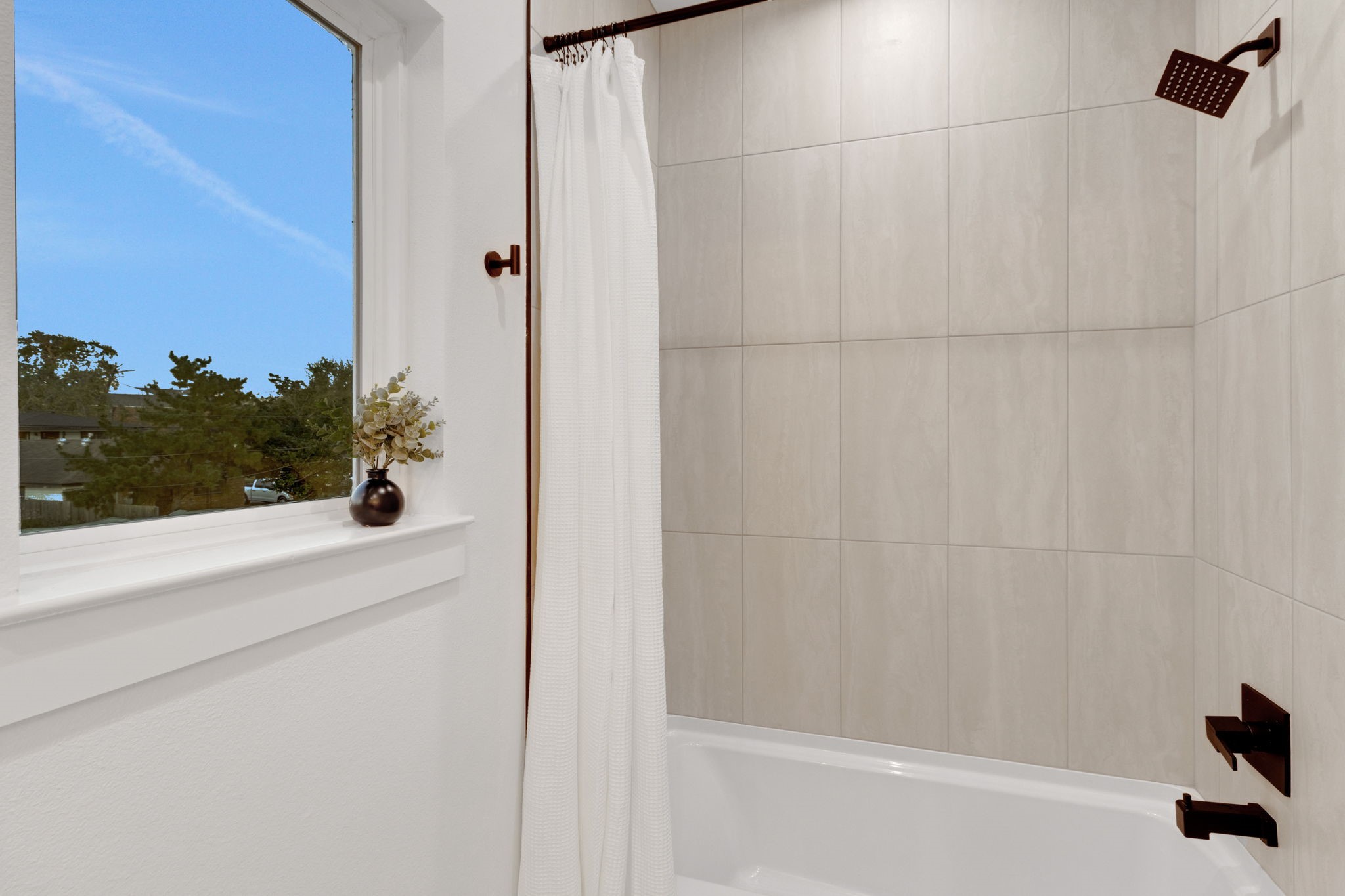 4202 Plaag Street Houston, TX 77016 - Photo 31 of 38 Full bath featuring a deep soaking tub with modern tile surround and a large window that brings in natural light, creating a relaxing retreat.