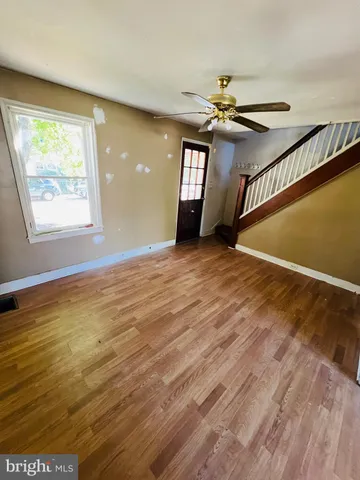 an empty room with wooden floor fan and windows