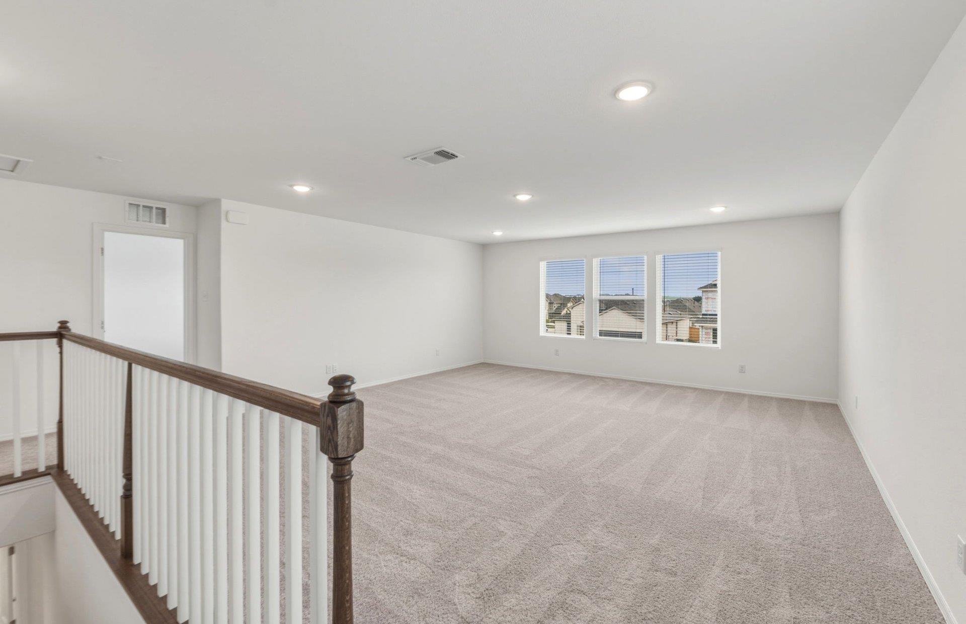 545 Henry Milton Road Georgetown, TX 78626 - Photo 12 of 33 A spacious upper-level loft features wall-to-wall carpeting and recessed lighting.