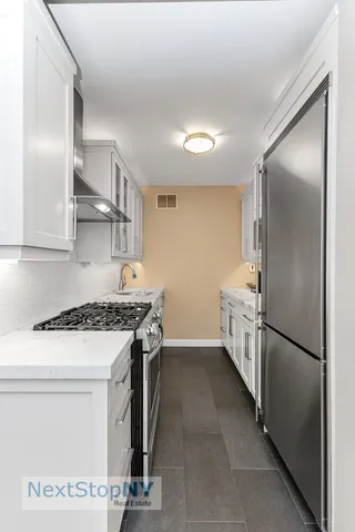 a kitchen with stainless steel appliances granite countertop a refrigerator a stove and a sink