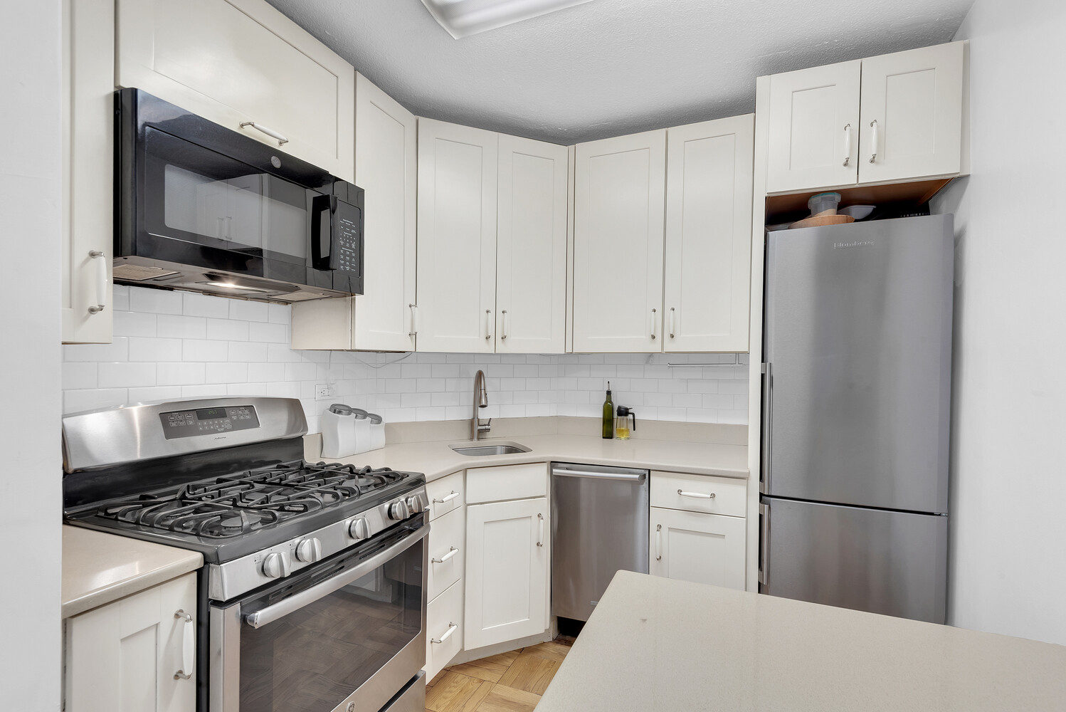 300 East 40th Street, Unit 6L Manhattan, NY 10016 - Photo 4 of 5 a kitchen with stainless steel appliances a sink a stove a microwave and cabinets