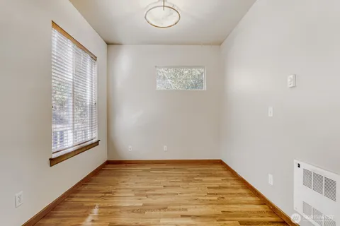 a view of an empty room with wooden floor and a window
