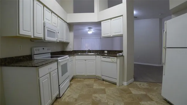 a kitchen with granite countertop white cabinets and white appliances