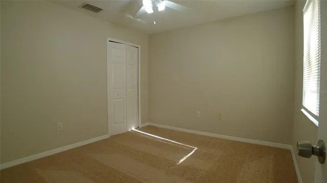 an empty room with a window and chandelier fan
