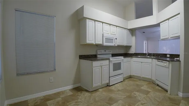 a kitchen with granite countertop white cabinets and white appliances