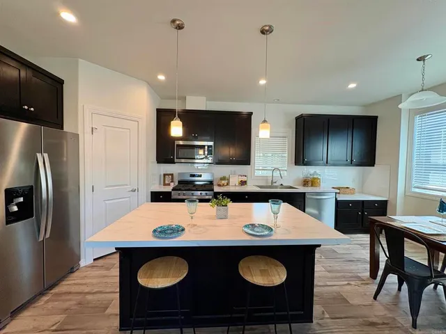 a kitchen with a sink a stove a refrigerator and chairs