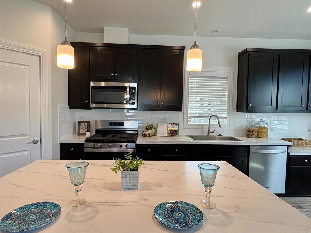 28890 Lilac Road, Unit 179 Valley Center, CA 92082 - Photo 4 of 21 a kitchen with stainless steel appliances kitchen island granite countertop a sink and a microwave