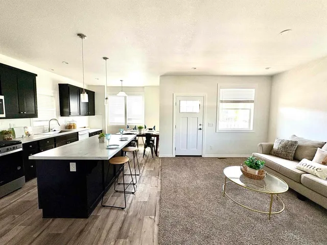 a living room with furniture a flat screen tv and kitchen view