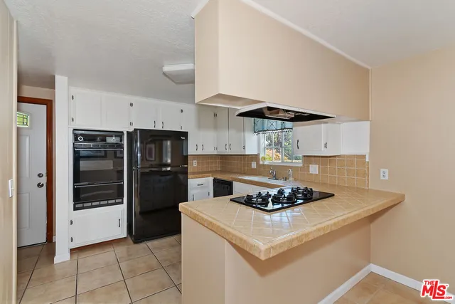 a kitchen with white cabinets and a stove with a sink