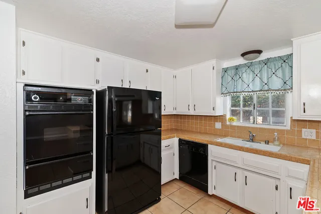 a kitchen with stainless steel appliances a stove and white cabinets