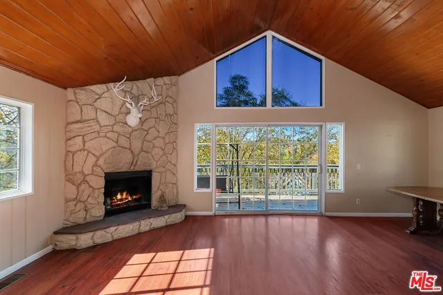 a view of an empty room with wooden floor fireplace and a window