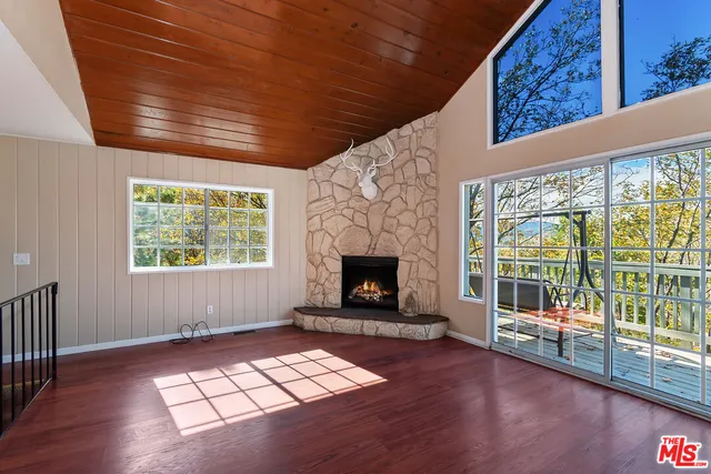 a view of an empty room with wooden floor fireplace and a window