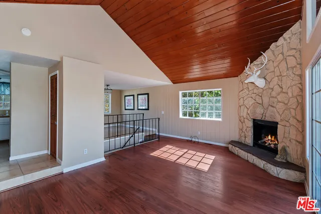 a view of an empty room with wooden floor fireplace and a window