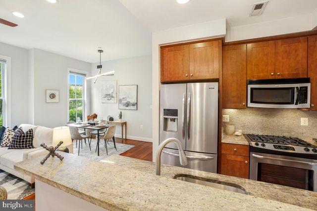 a kitchen with stainless steel appliances granite countertop a stove top oven a sink dishwasher a dining table and chairs with wooden floor