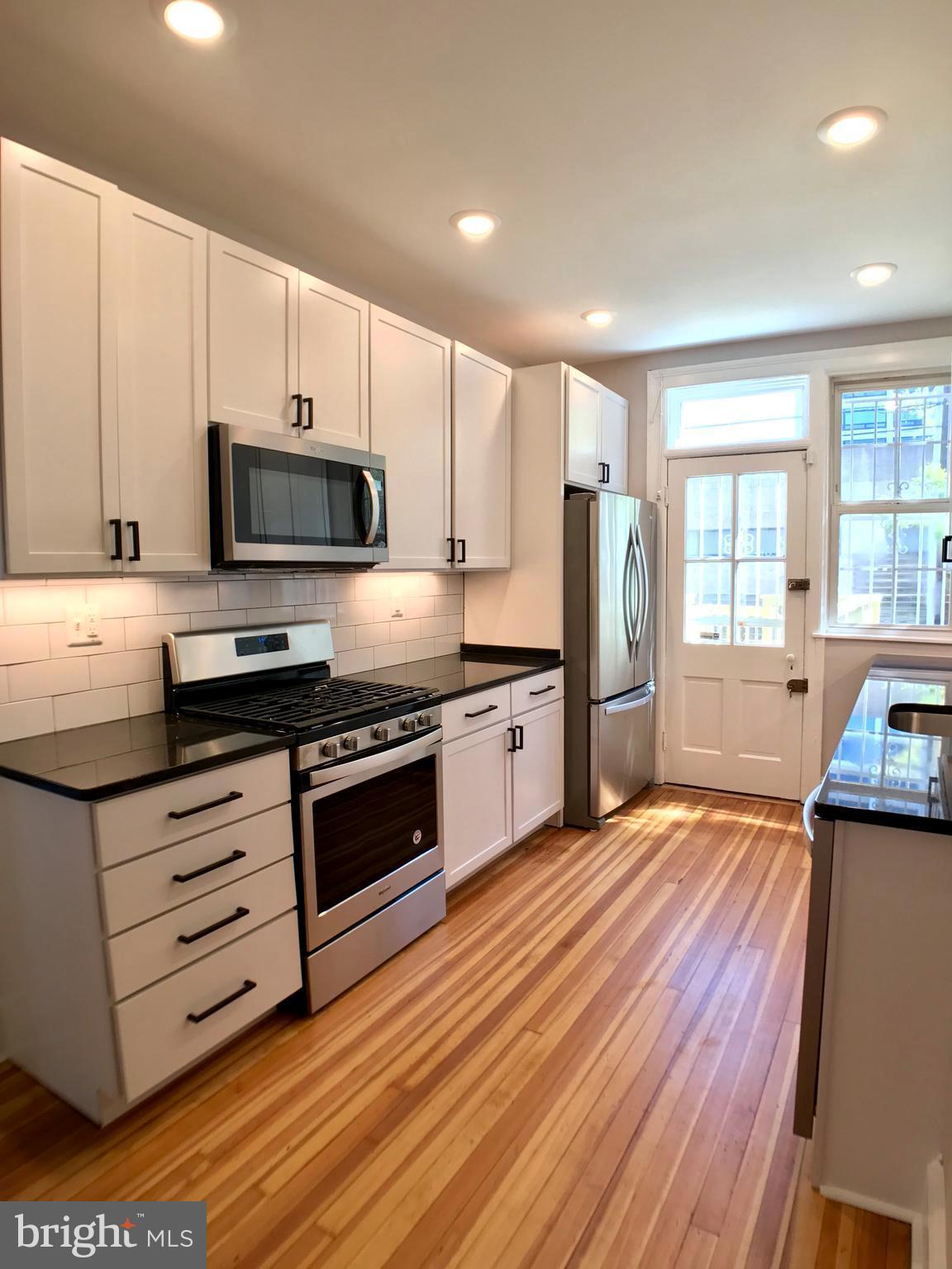 3959 Cloverhill Road Baltimore, MD 21218 - Photo 9 of 27 a kitchen with stainless steel appliances a stove a sink a refrigerator white cabinets and wooden floor