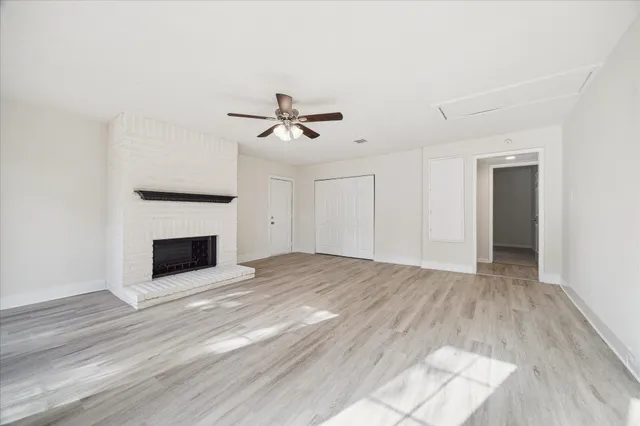 a view of an empty room with wooden floor and a fireplace
