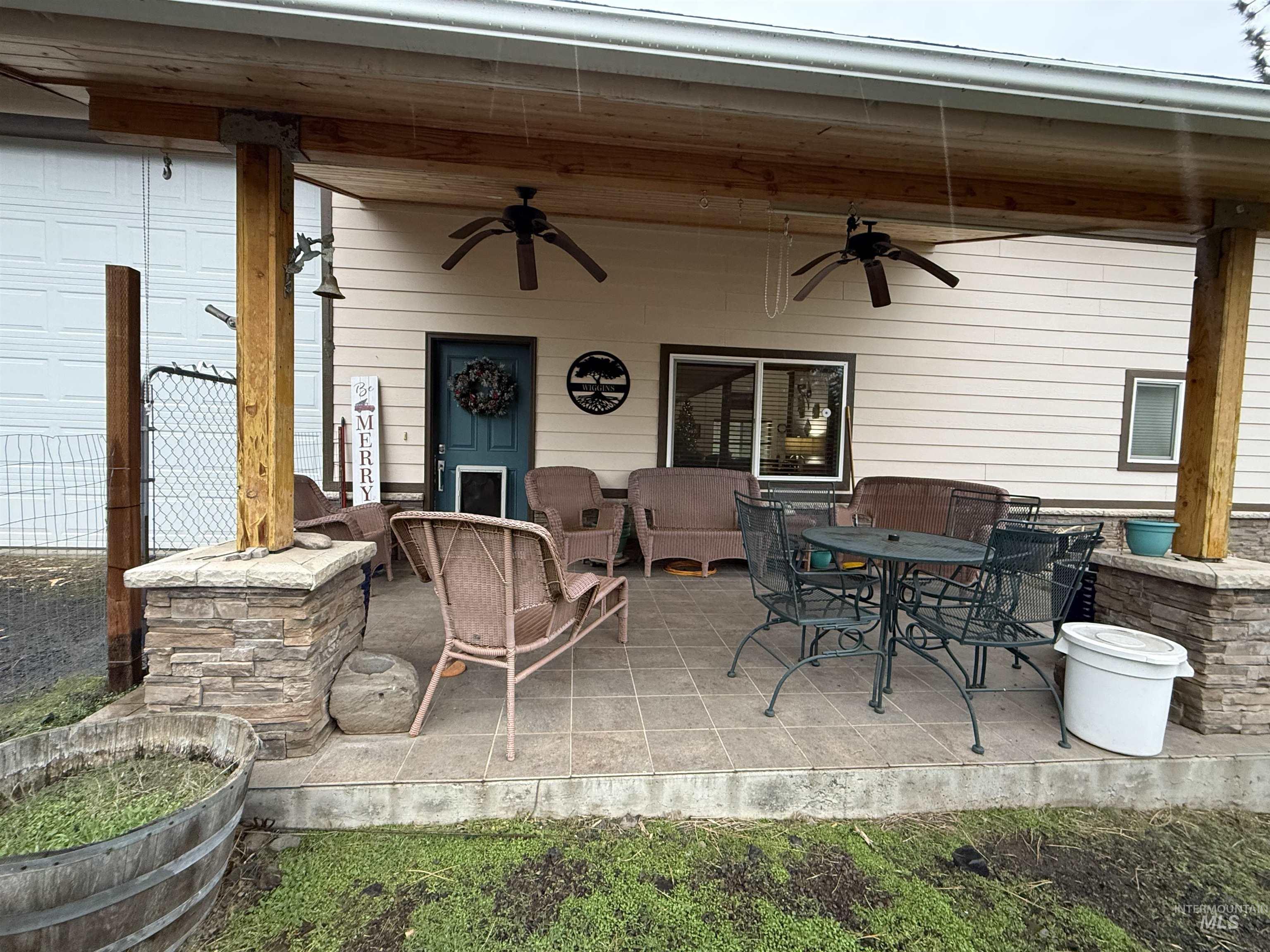 Expansive outdoor area featuring a two-bay detached garage with roll-up doors, a large barn-style structure with an integrated covered porch, and mature trees
