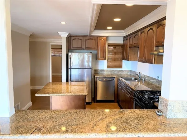 a kitchen with stainless steel appliances kitchen island granite countertop a sink refrigerator and cabinets