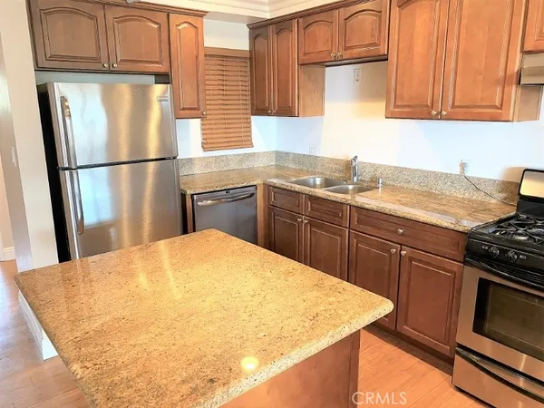a kitchen with granite countertop a refrigerator stove top oven and sink
