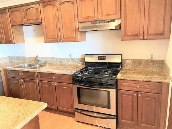 a kitchen with granite countertop a stove top oven cabinetry a sink and dishwasher