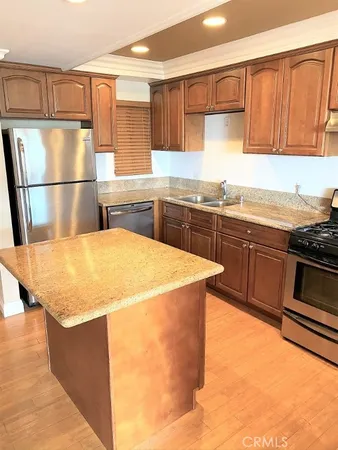 a kitchen with stainless steel appliances granite countertop a sink dishwasher stove top oven and cabinets with wooden floor