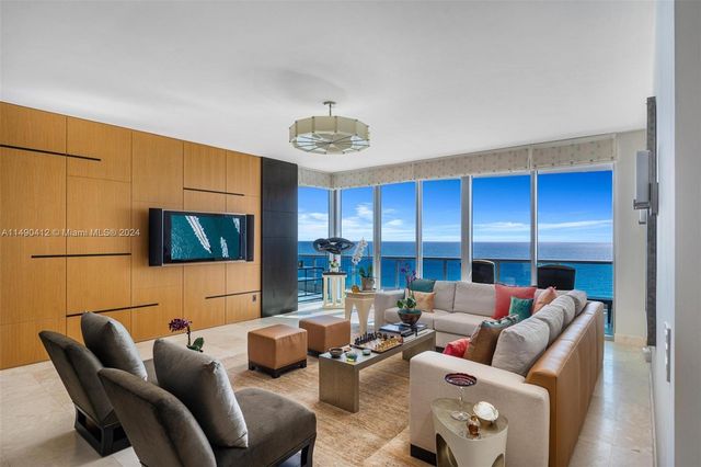 a living room with furniture a floor to ceiling window and a flat screen tv