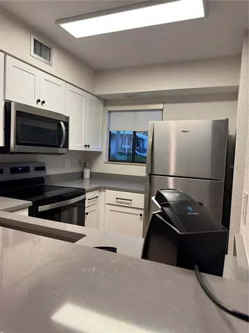 a kitchen with a refrigerator and a stove top oven