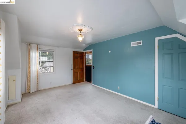 an empty room with chandelier fan and windows