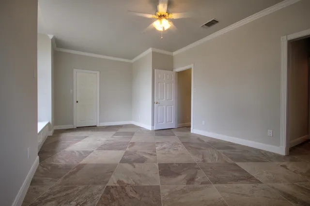 a view of an empty room and chandelier fan
