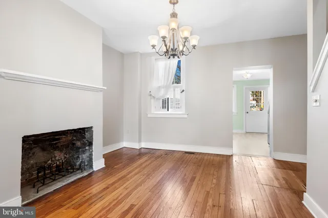 a view of an empty room with wooden floor fireplace and a window