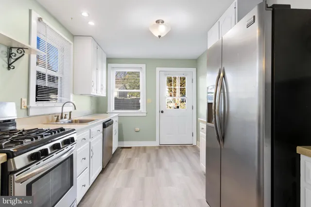 a kitchen with stainless steel appliances granite countertop a stove a refrigerator and a sink with wooden cabinets