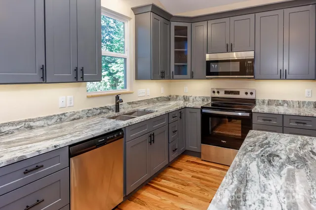 a kitchen with stainless steel appliances granite countertop a sink stove and microwave