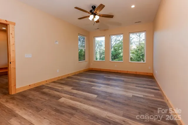 a view of an empty room with wooden floor and windows