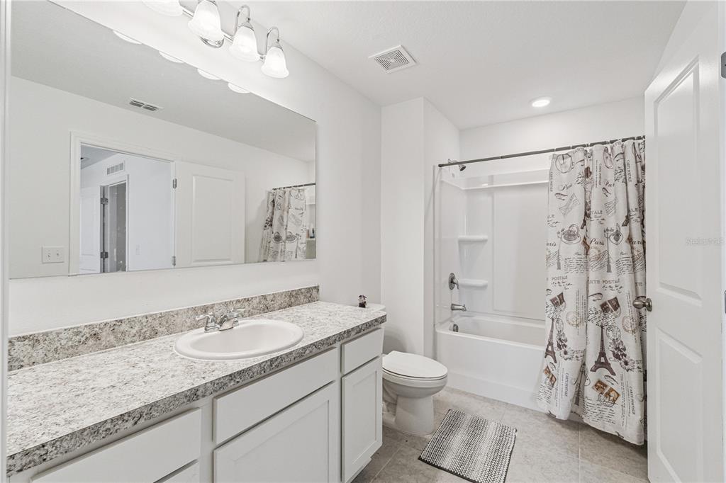 5931 Chestnut Grv Place St. Cloud, FL 34771 - Photo 14 of 20 a bathroom with a granite countertop sink a toilet a mirror a bathtub and shower