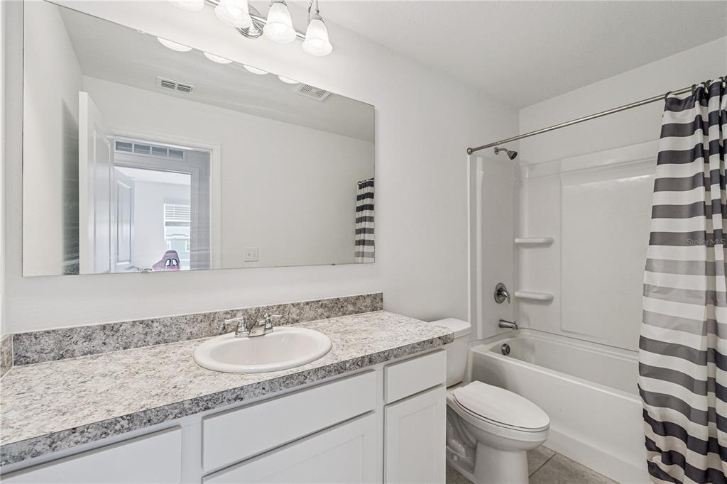 5931 Chestnut Grv Place St. Cloud, FL 34771 - Photo 17 of 20 a bathroom with a granite countertop sink toilet a mirror a vanity and shower