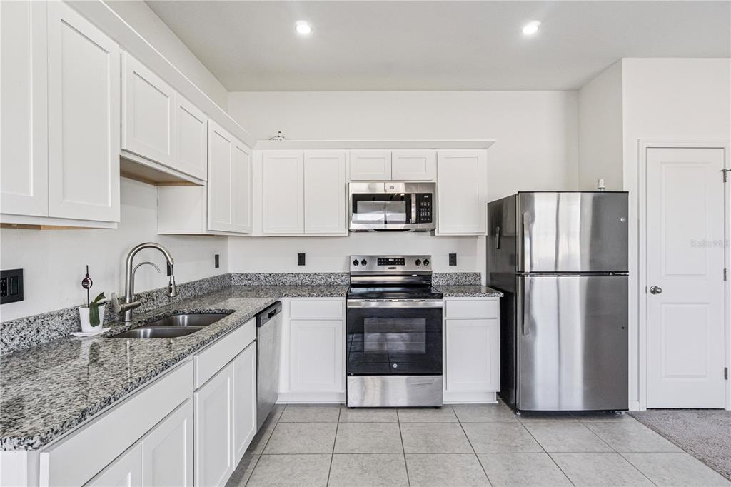 5931 Chestnut Grv Place St. Cloud, FL 34771 - Photo 5 of 20 a kitchen with stainless steel appliances granite countertop a refrigerator sink and stove