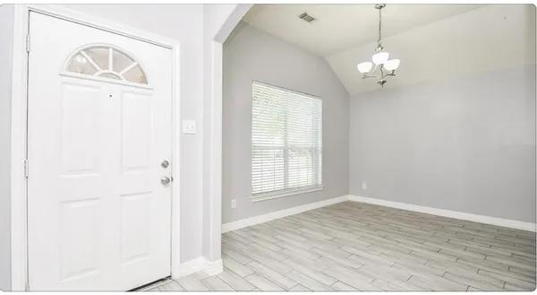 an empty room with wooden floor cabinet and windows