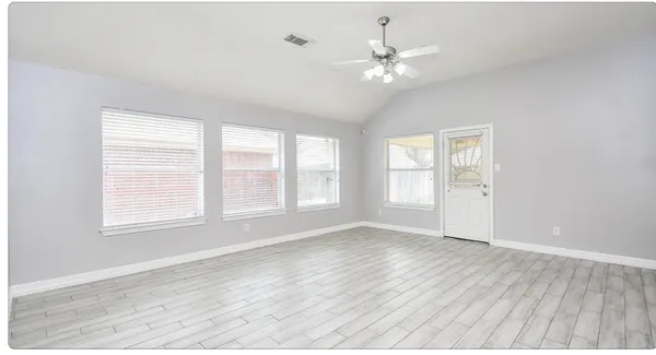 a view of an empty room with wooden floor and a window