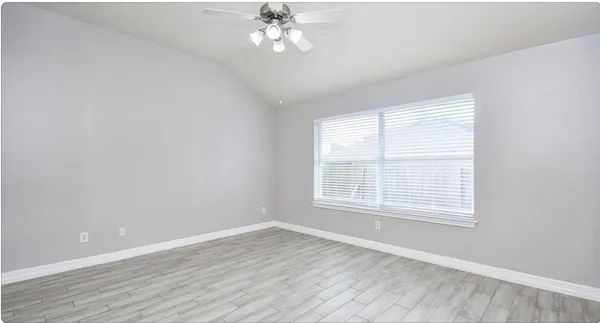 an empty room with wooden floor and windows