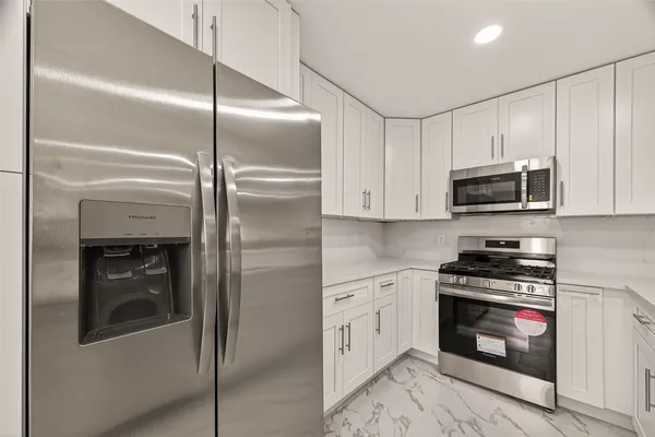 a kitchen with stainless steel appliances granite countertop a refrigerator a stove and a sink with wooden floor