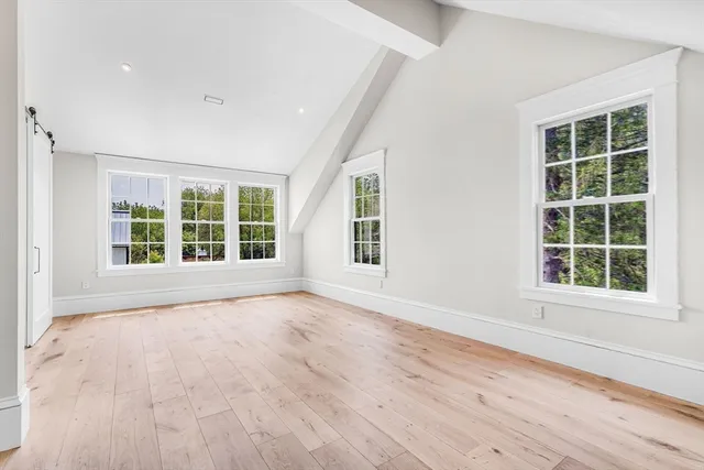 a view of an empty room with wooden floor and windows